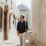 Expat Walking Beside A Modern Muscat Street In Warm Daylight